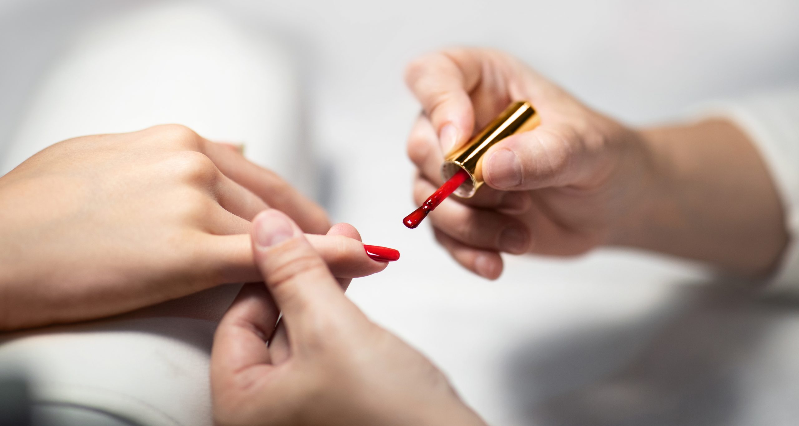 Closeup Of Manicurist And Client's Female Hands Applying Red Gel Polish, Caring For Nails At Modern Beauty Salon Indoors. Woman Enjoys Manicure Routine At Nail Studio. Selective Focus, Panorama